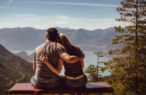 geliefden bij elkaar op een bankje met uitzicht over een meer en dal.
